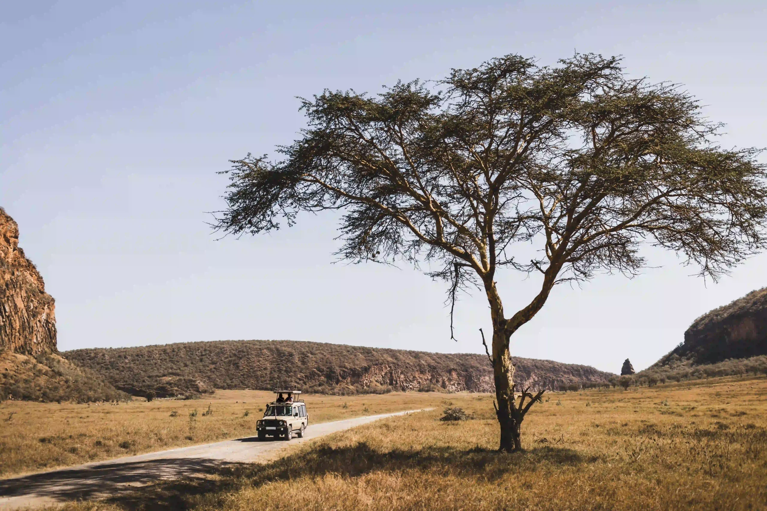 Safari vehicle driving between cliffs at sunrise